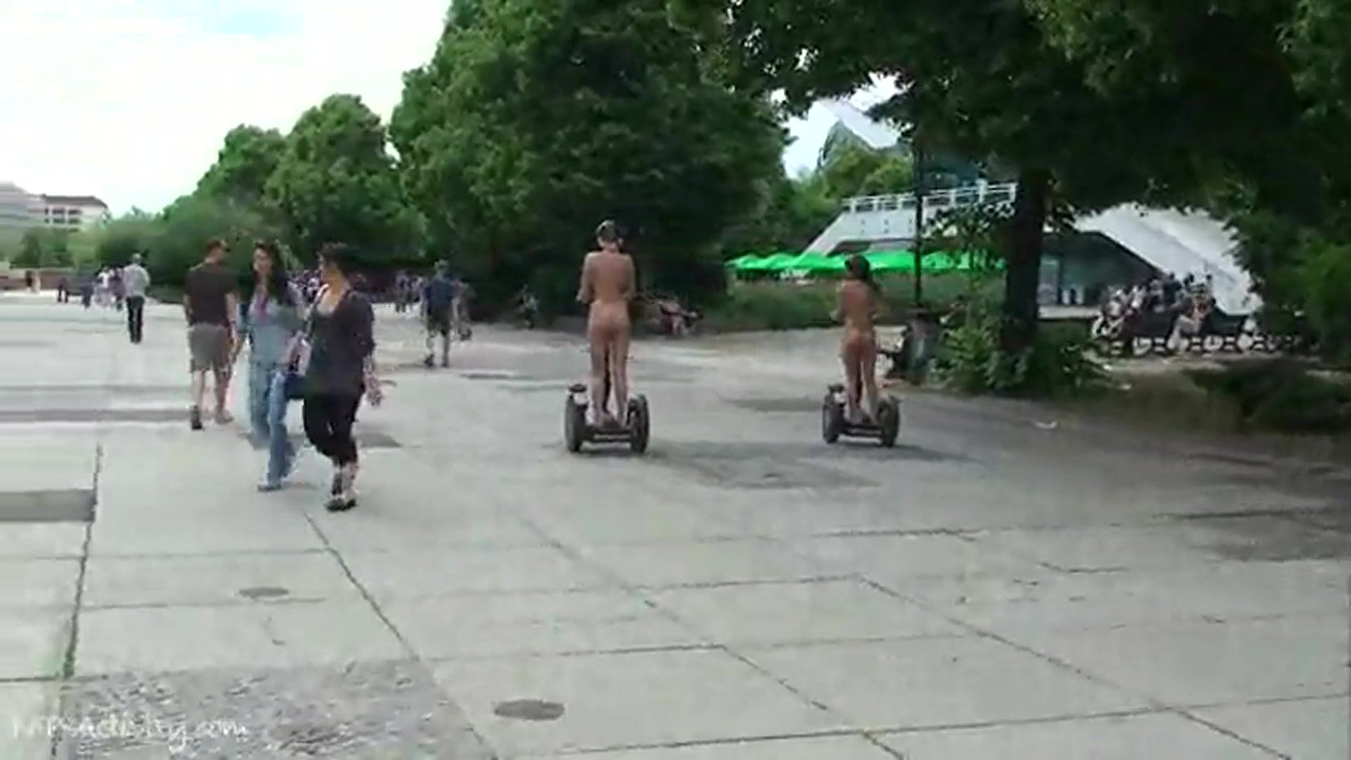 Two Girls Walk Naked Down The Street Riding A Skateboard